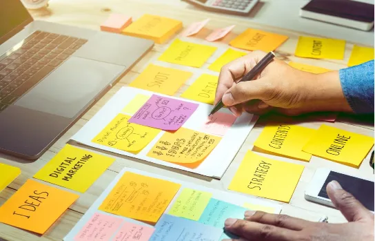 Person arranging colorful sticky notes on a whiteboard during a planning or brainstorming session