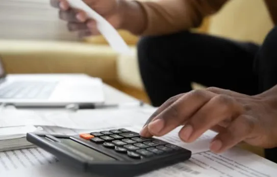 Person using calculator while reviewing financial documents during business meeting